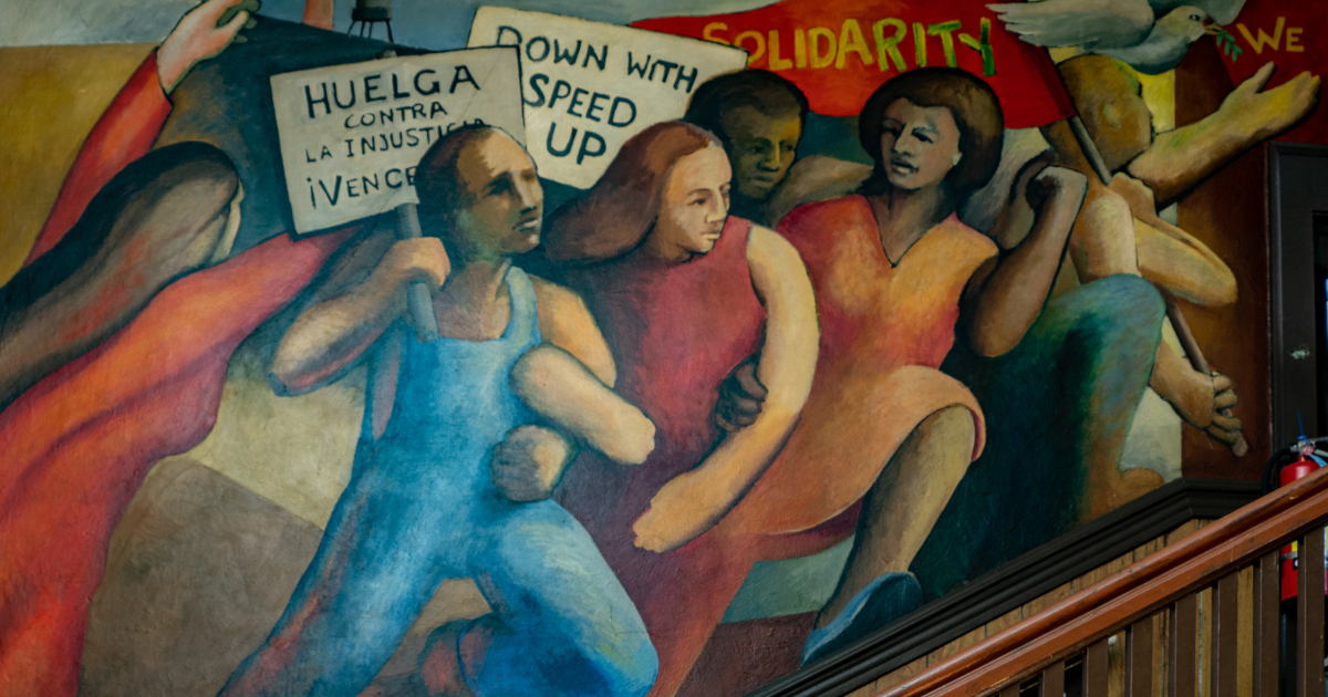 A painted mural showing men and women holding protest signs